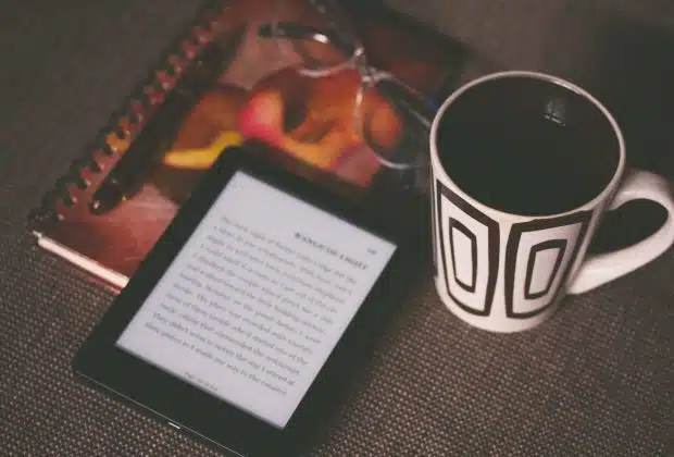 black E-book reader beside white and black mug